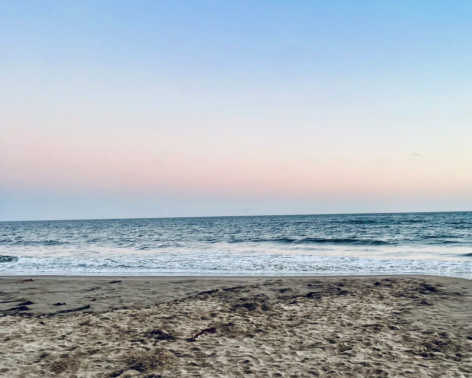 A quiet beach under a pastel evening sky.